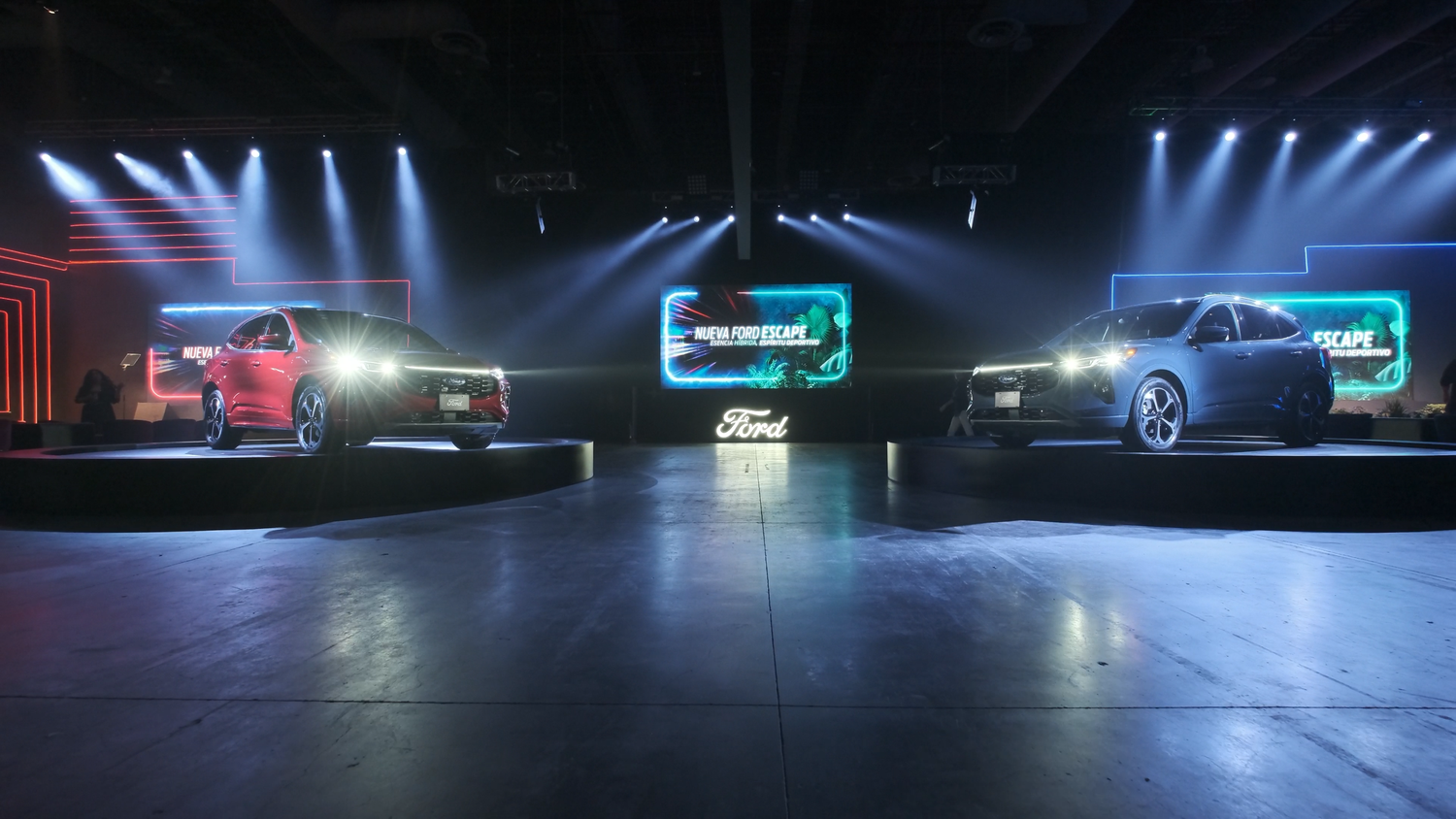 Two Ford vehicles displayed on a dramatic stage with colorful lighting at an auto launch event.