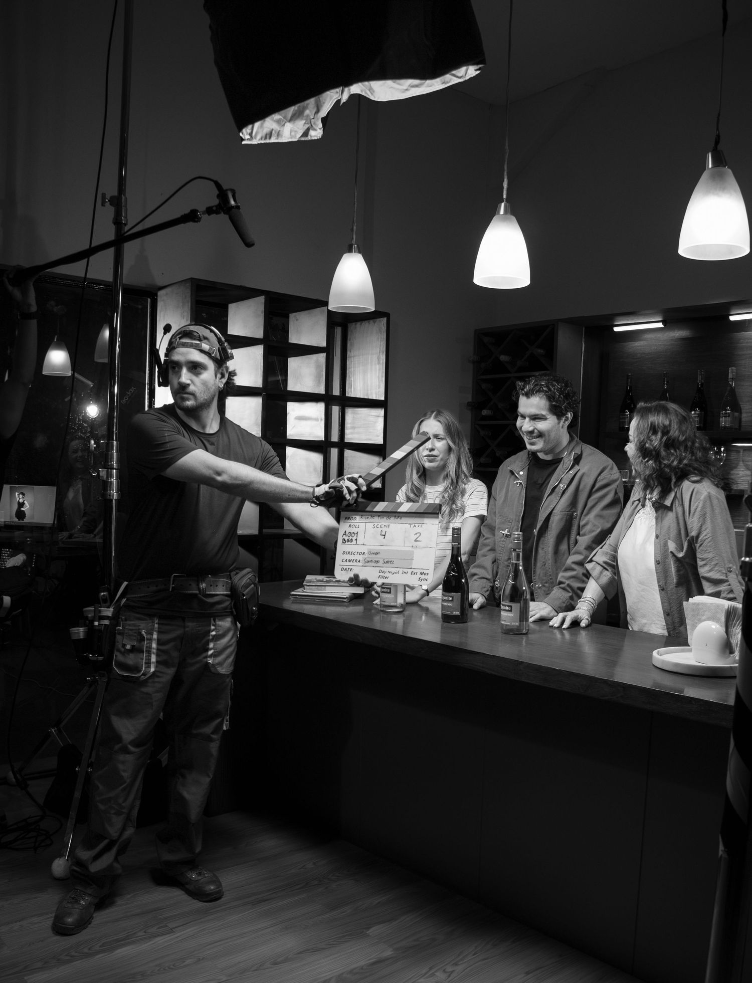 Black and white behind-the-scenes film set with crew and actors at a bar counter.