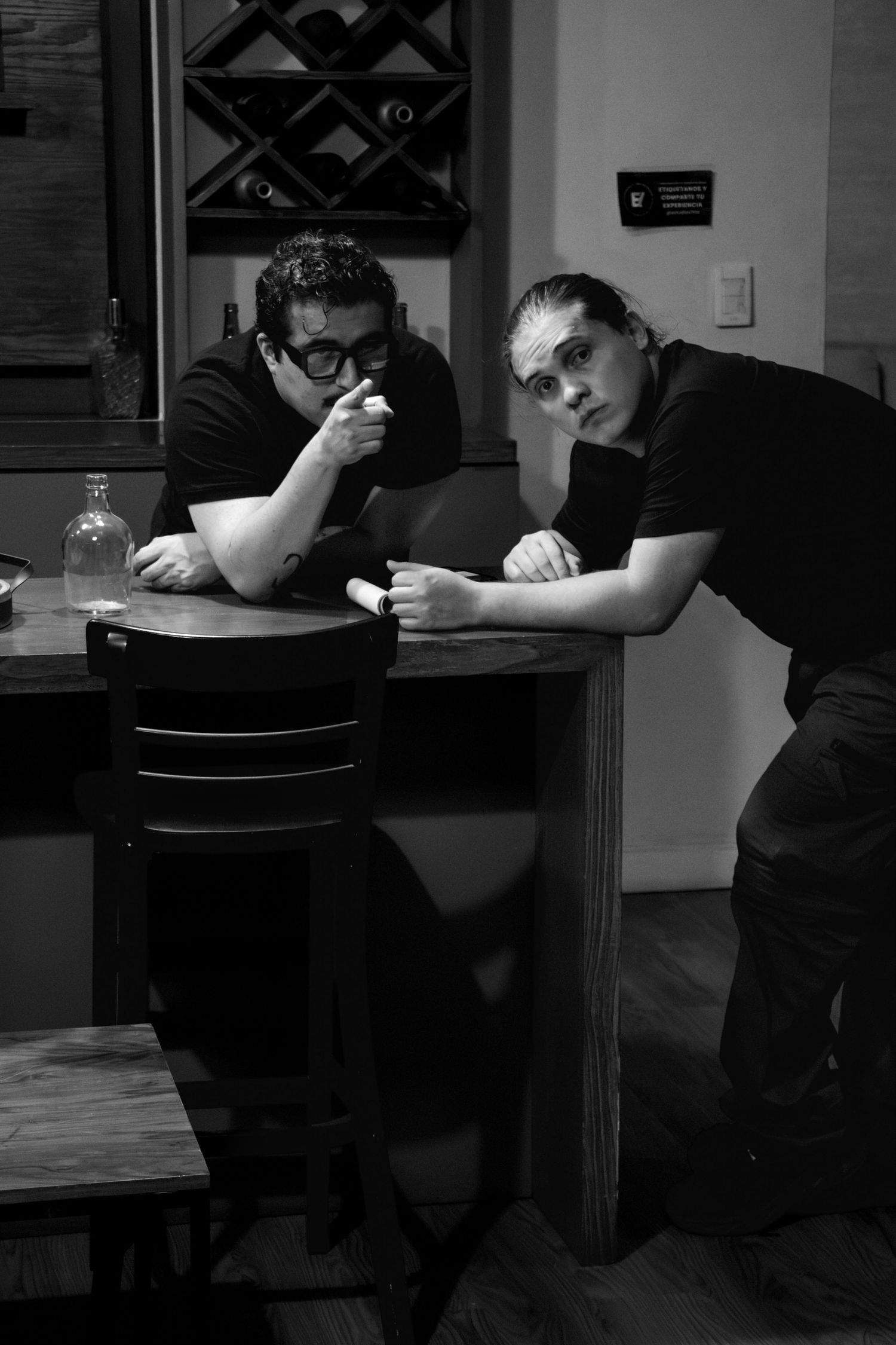 Two film crew members lean on a bar counter reviewing details during a production shoot.