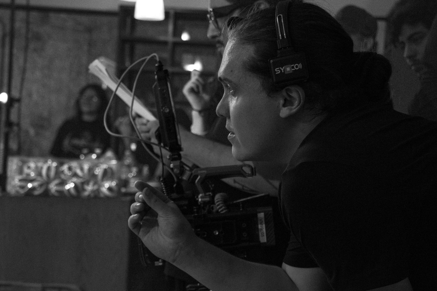Black and white photo of a cinematographer operating a camera on a film set.