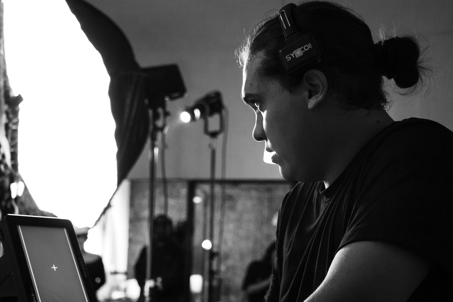 Black and white photo of filmmaker reviewing footage on laptop during film production set.