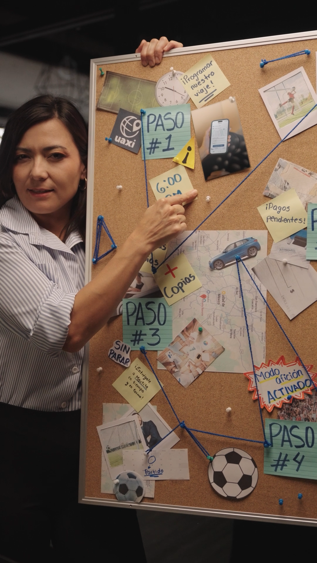 Woman holds large cork bulletin board displaying organized steps and notes with string connections.