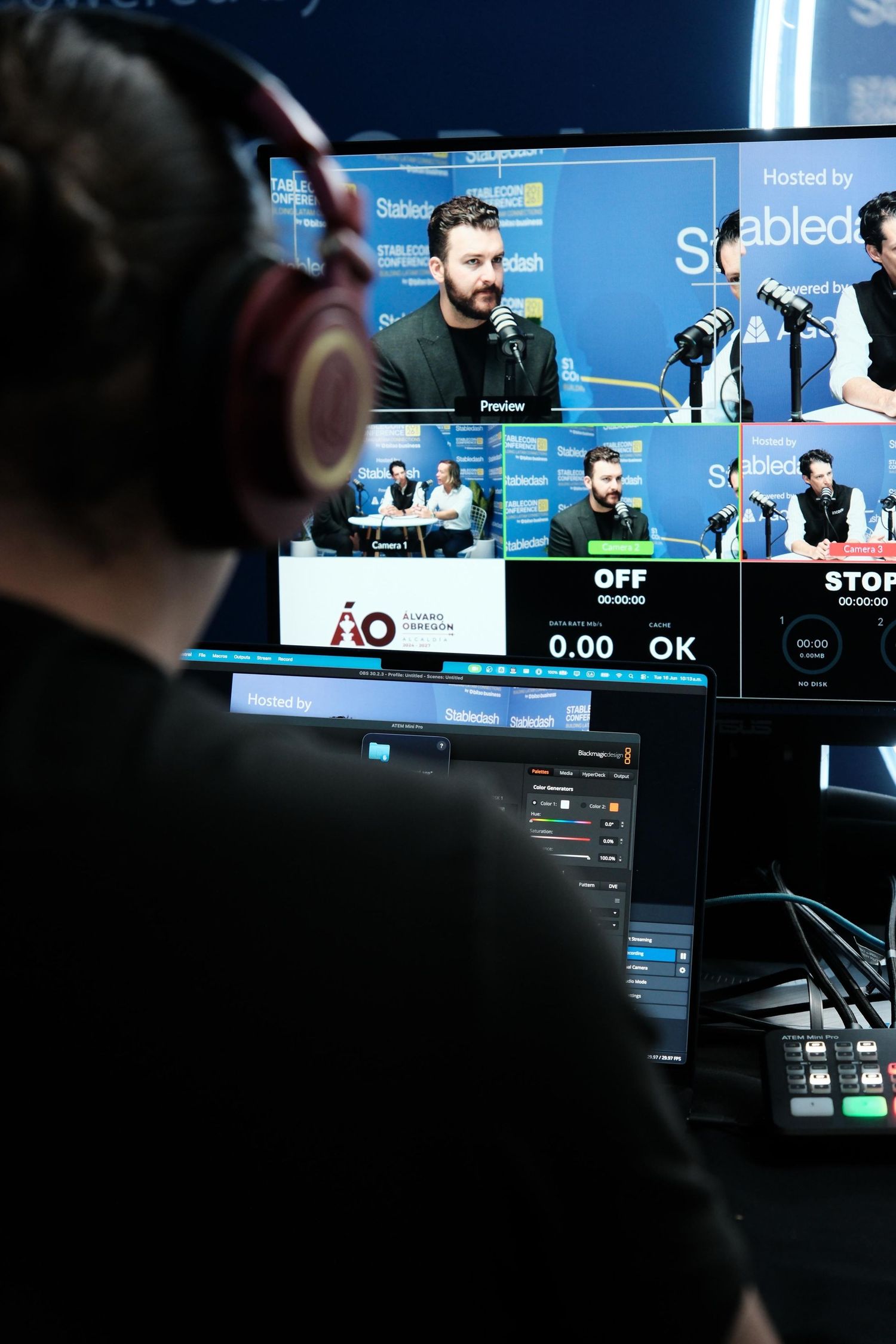 A video producer monitors multiple screens at a podcast production control station during the Stabledash Stablecoin Conference.