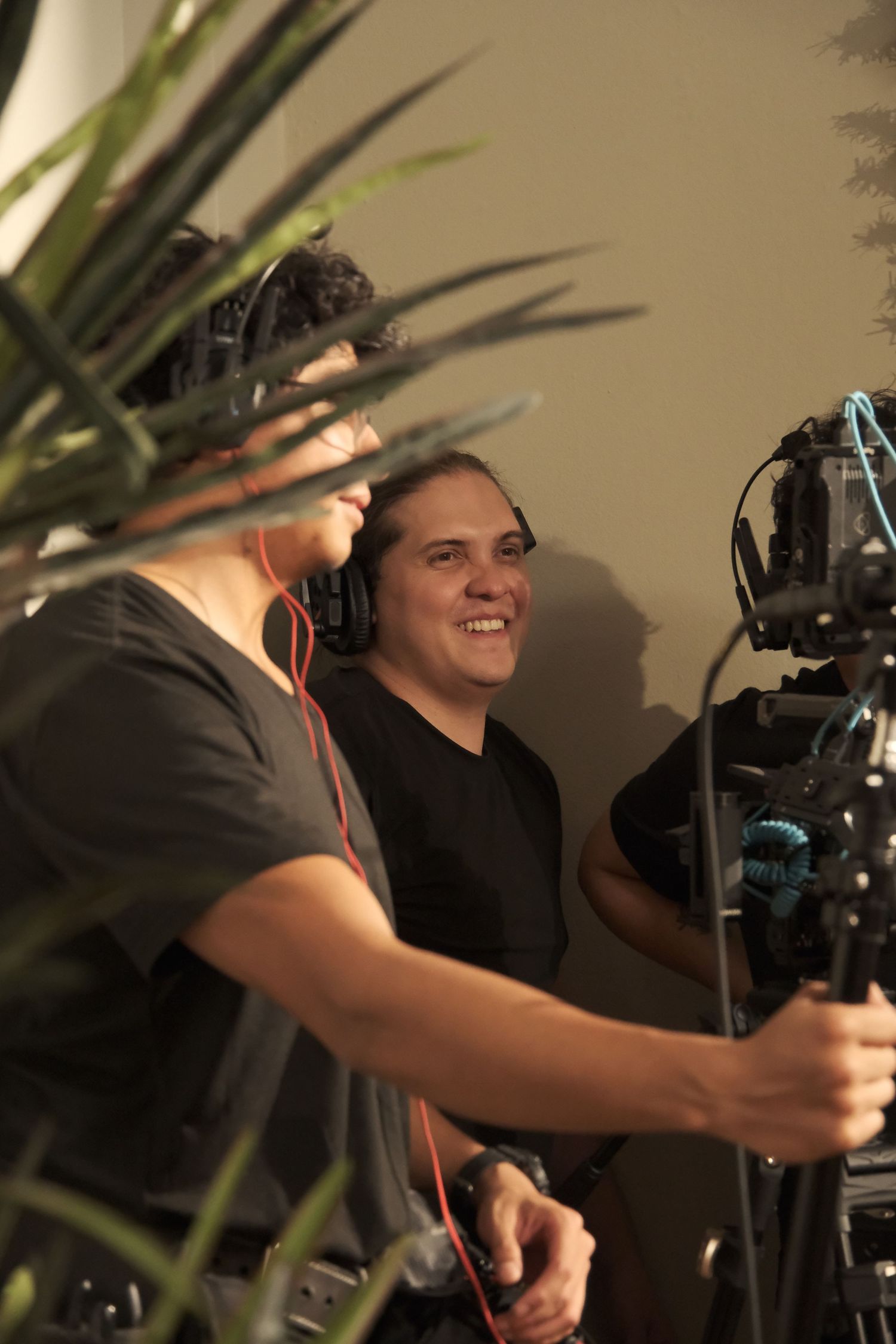 Two male film crew members smiling while operating camera equipment on a professional movie set.