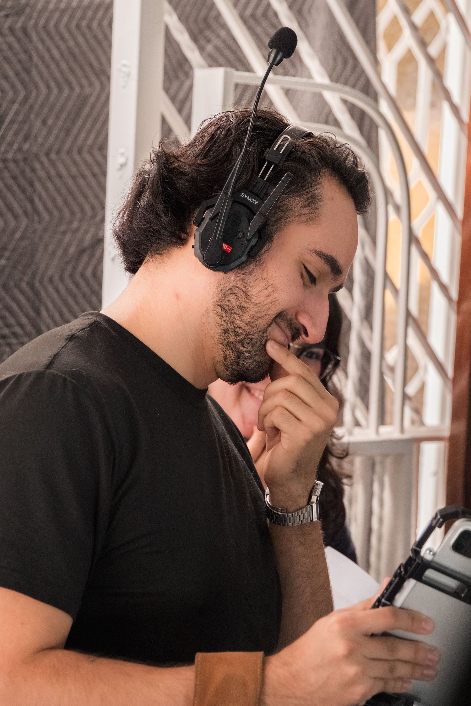 Male film director wearing a headset microphone reviews script during a video production.