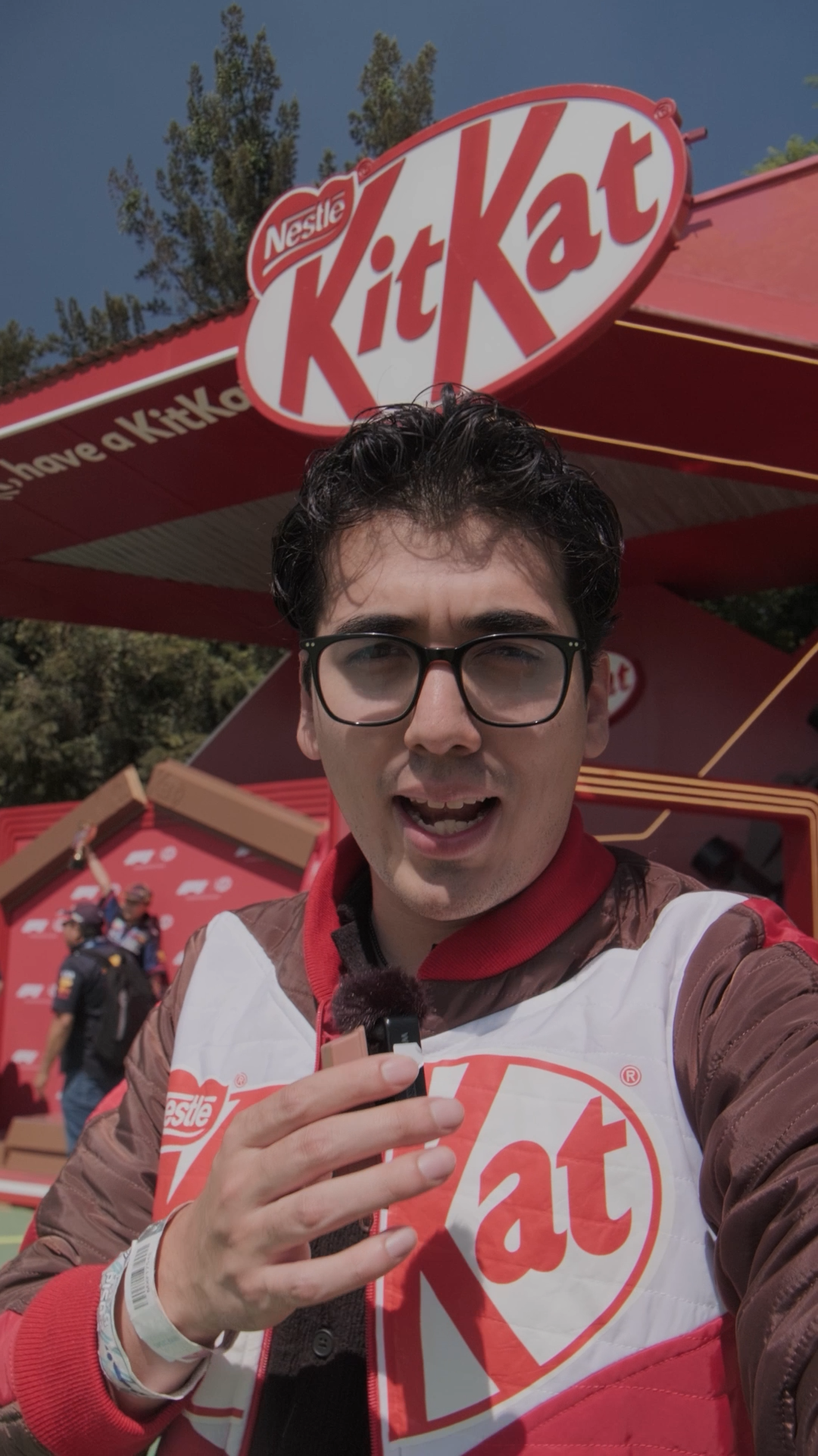 Young man wearing KitKat branded vest holds chocolate bar at a Nestle KitKat outdoor promotional event.