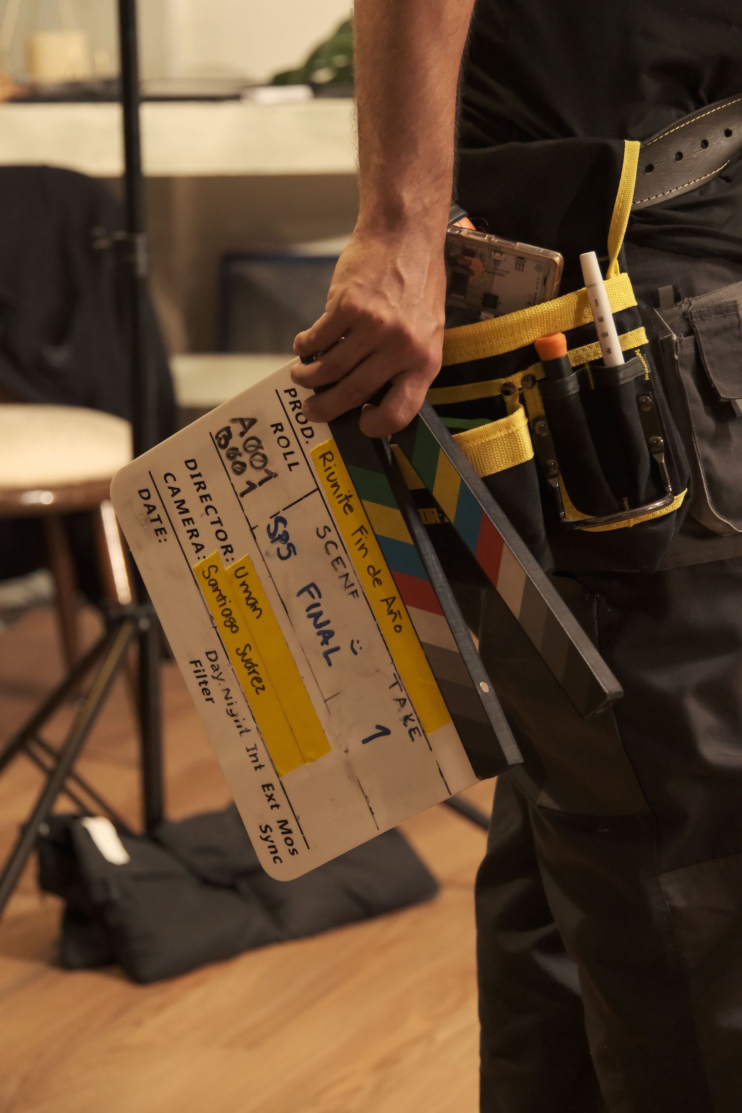 Film crew member holding a clapperboard with a tool belt on a movie production set.