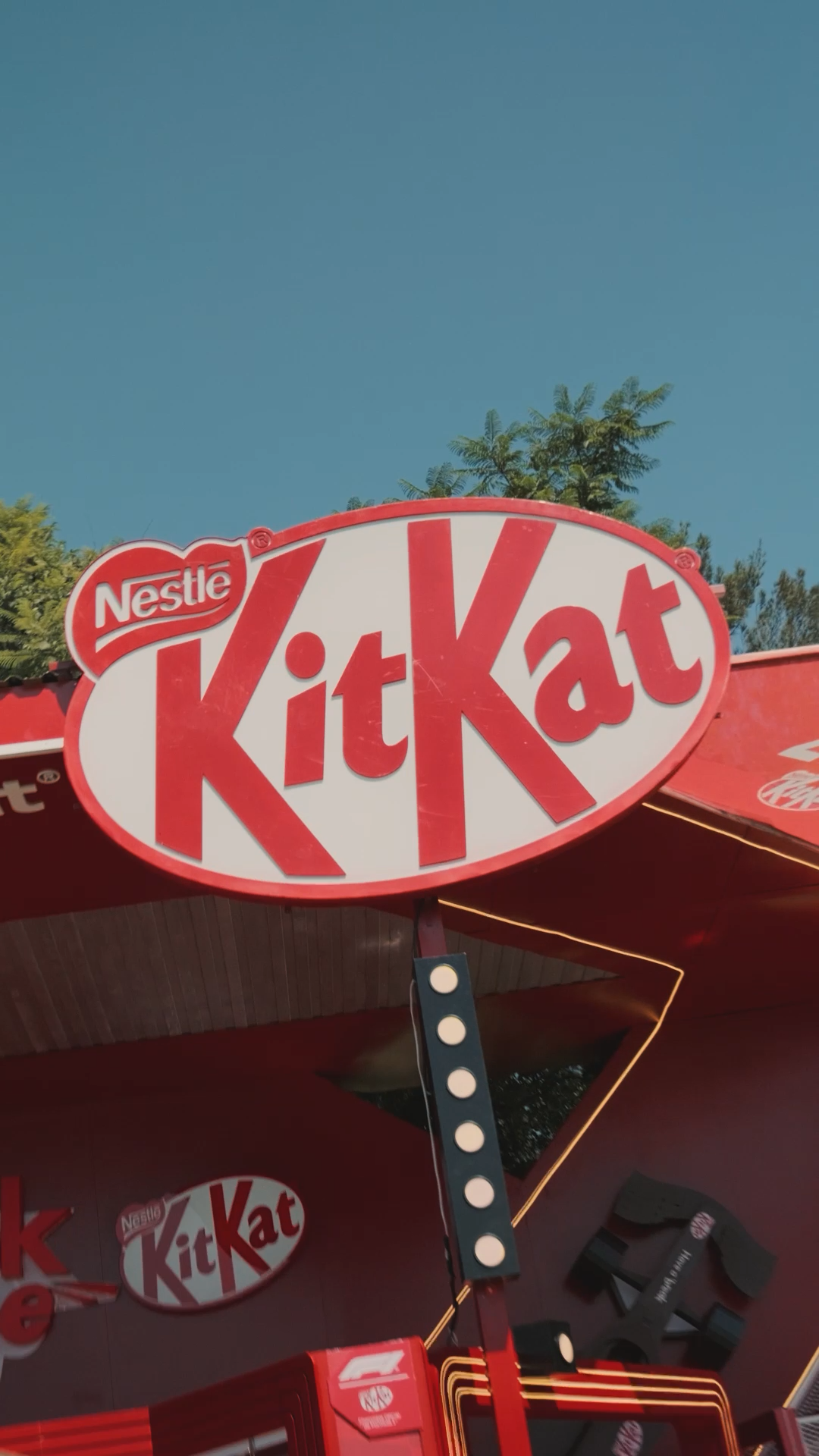 Large Nestle KitKat branded red sign displayed outdoors against a clear blue sky.