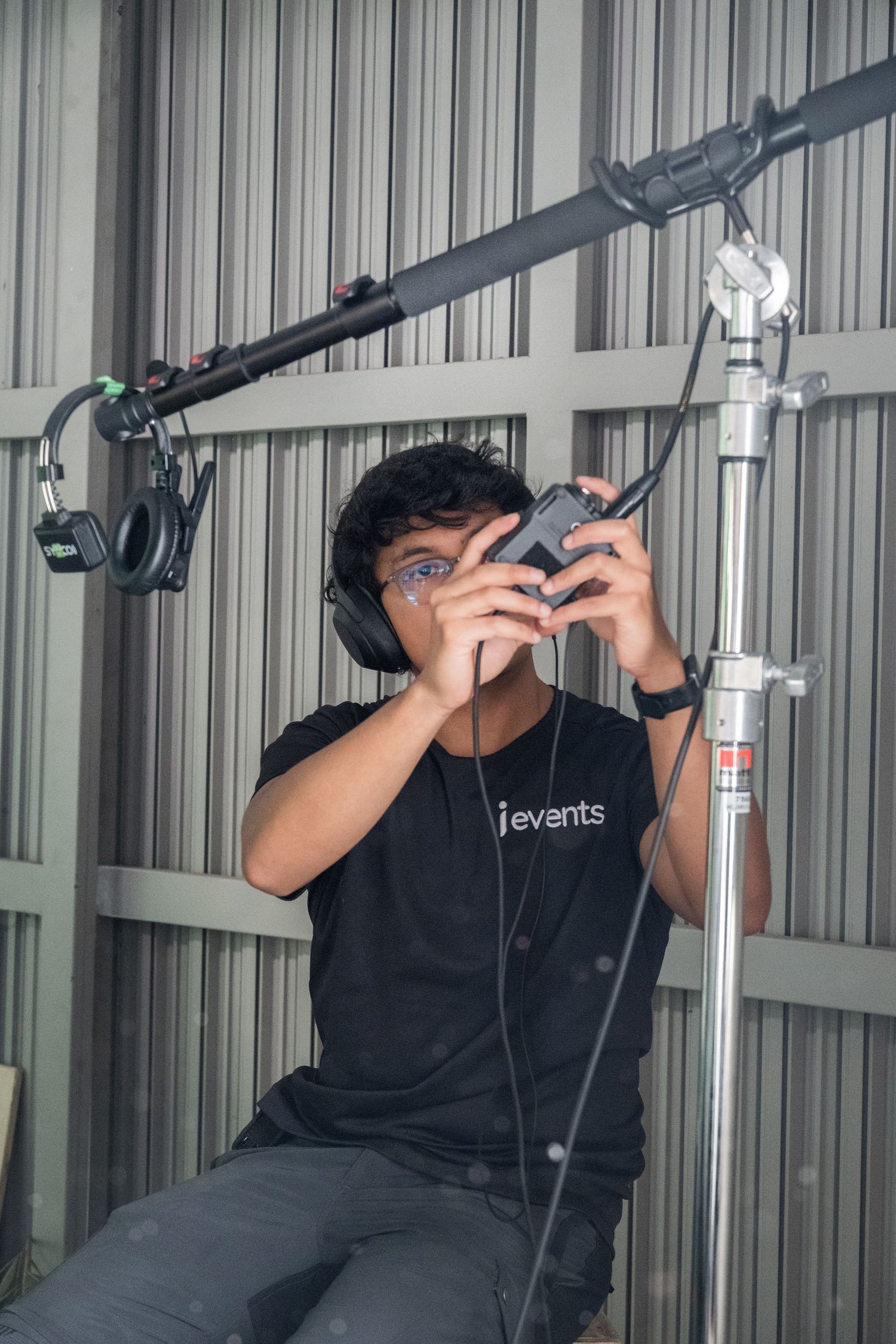 Young filmmaker wearing headphones reviews footage on a smartphone on a film production set.