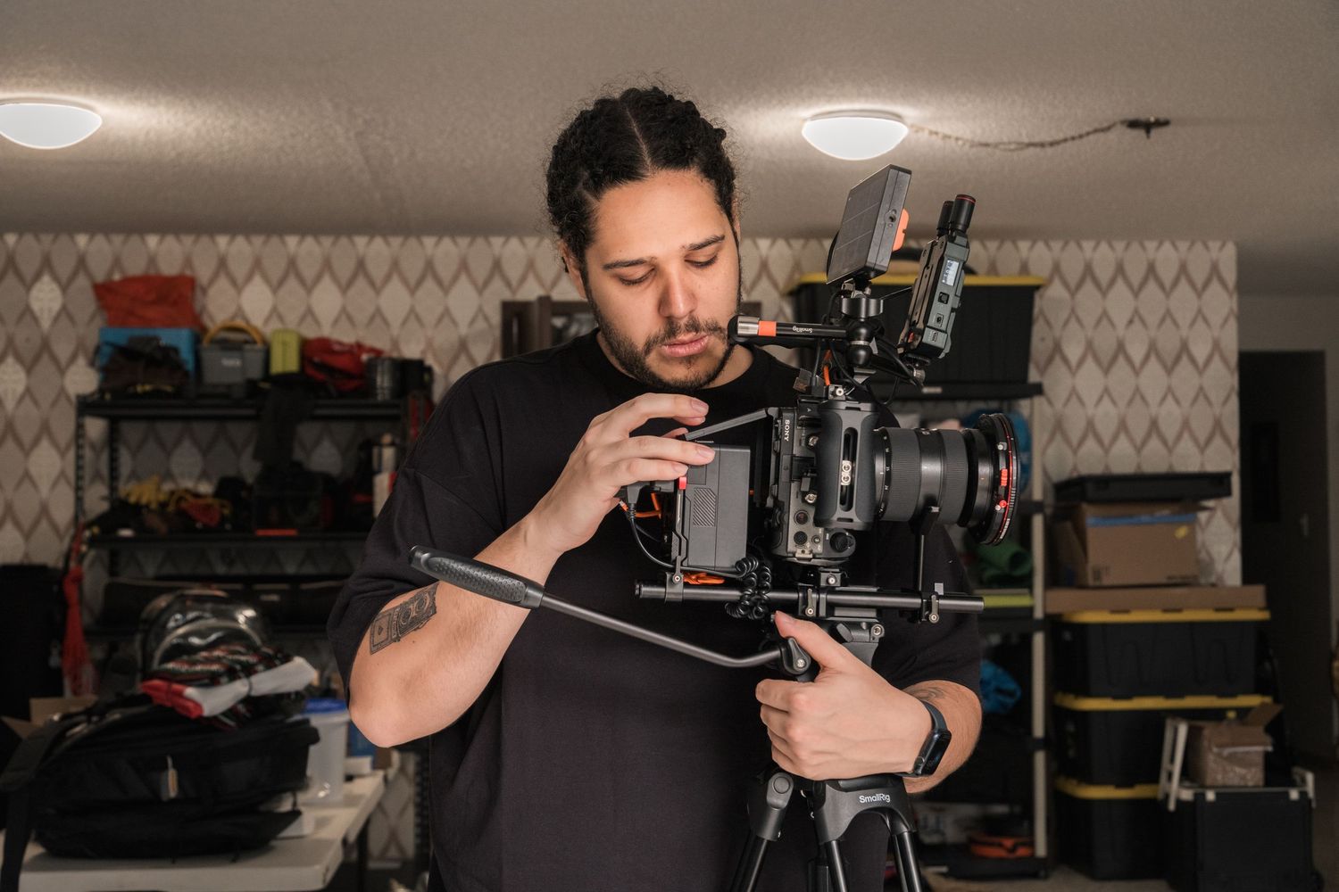 Male videographer adjusts a professional cinema camera on a tripod in an indoor studio.