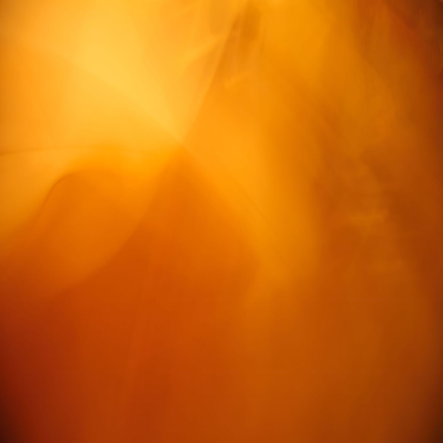 Abstract golden orange background with soft glowing light rays and shadowy geometric shapes creating a warm ethereal effect.