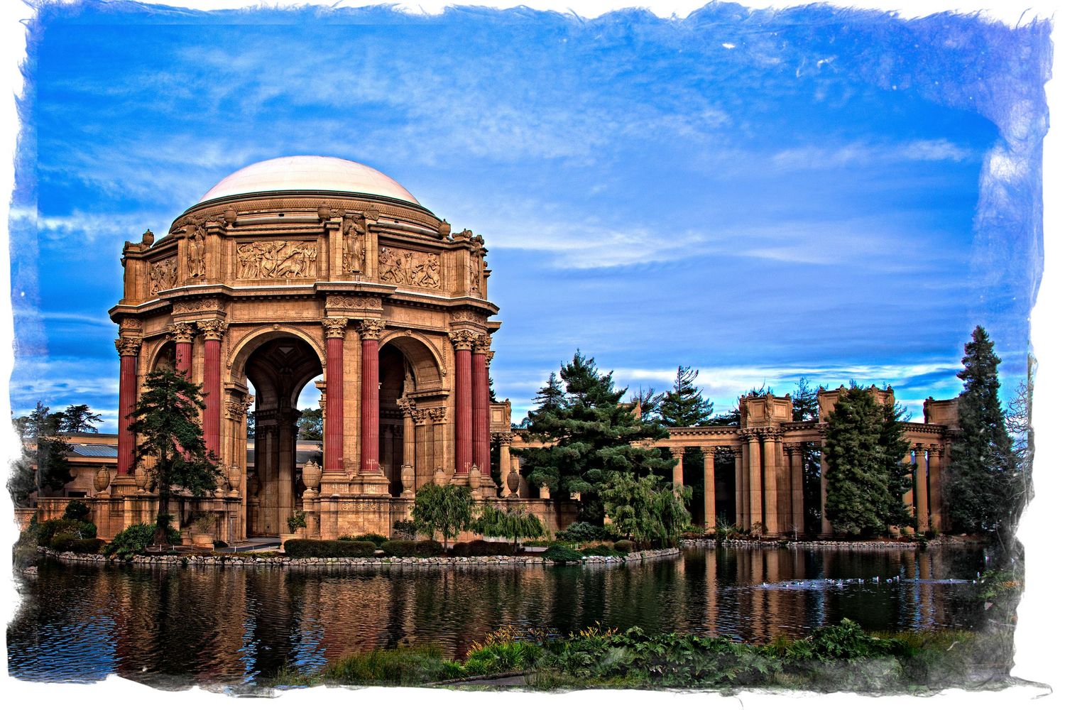 The Palace of Fine Arts rotunda reflected in a lagoon under dramatic blue skies in San Francisco.