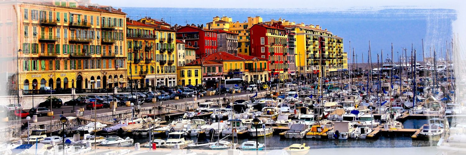 Panoramic view of Nice harbor with colorful buildings and yachts moored along the waterfront.
