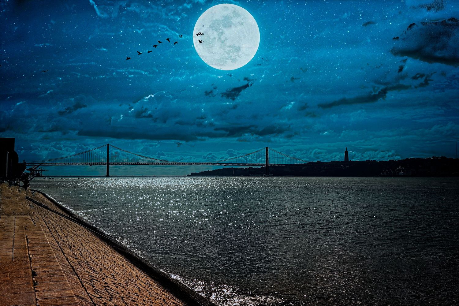 Full moon rising over the Tagus River in Lisbon with the 25 de Abril Bridge at night.