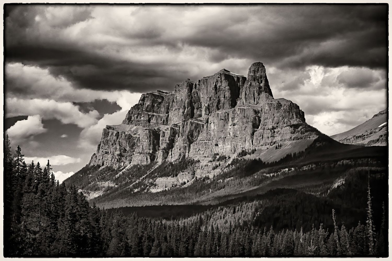 Black and white dramatic landscape of Castle Mountain in Banff National Park under stormy clouds in Canada.