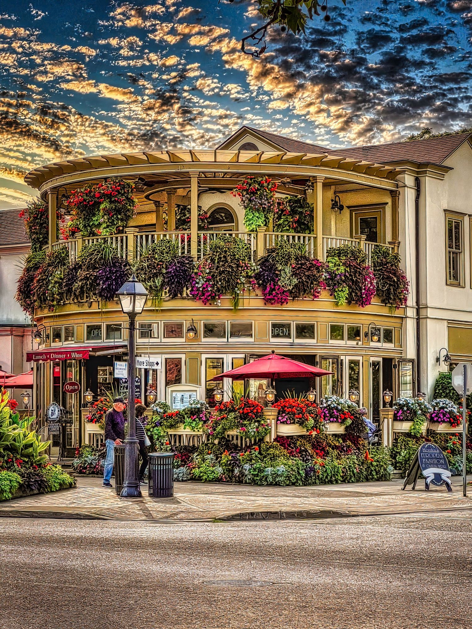 Charming curved building adorned with colorful hanging flowers and balconies at sunset in HDR.