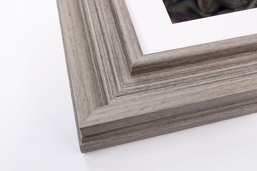 Light gray wood grain picture frame corner with white mat and photo on white background.