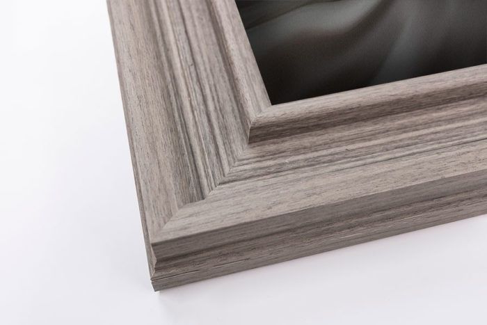 Light gray wood grain wide picture frame corner with carved stepped molding profile detail.