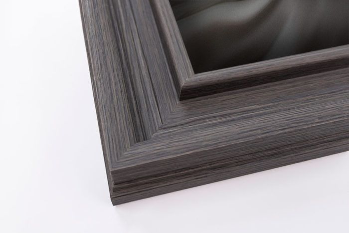 Dark gray wood grain wide picture frame corner with stepped inner edge detail.