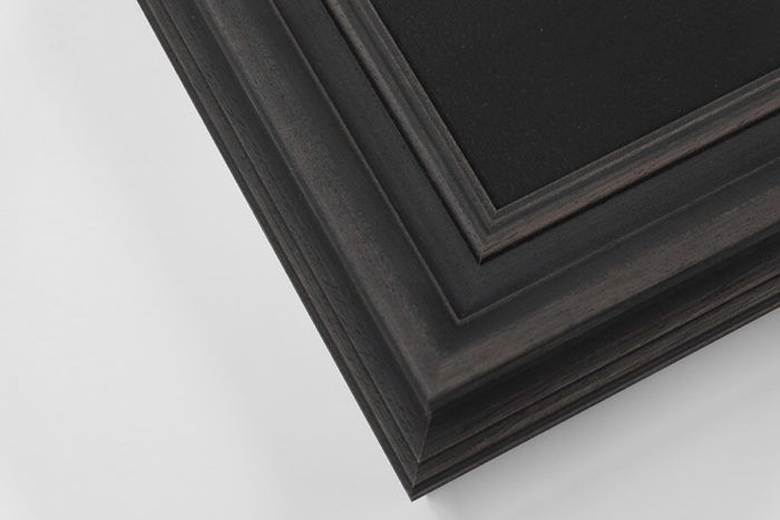 Black distressed wood ornate picture frame corner with layered stepped molding detail.