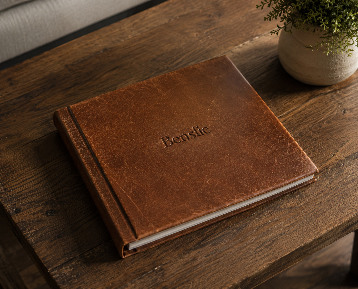 Personalized brown leather pet photo album with embossed name on a rustic wooden table.