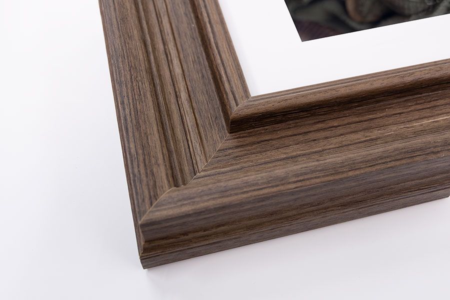 Warm brown wood grain picture frame corner with white mat and photo on white background.