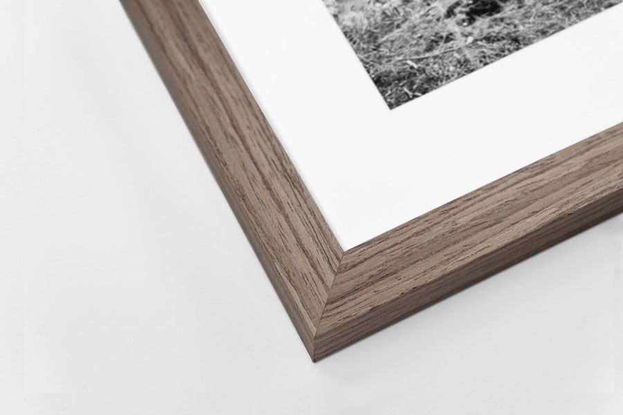 Warm brown walnut wood grain picture frame corner with white mat and black and white photo.