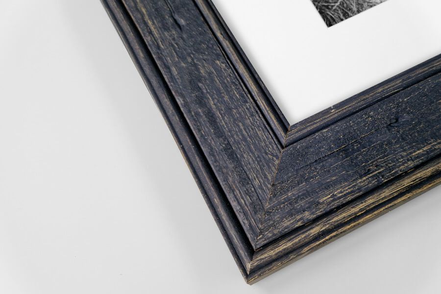 Dark navy distressed wood picture frame corner with white mat and photo on white background.