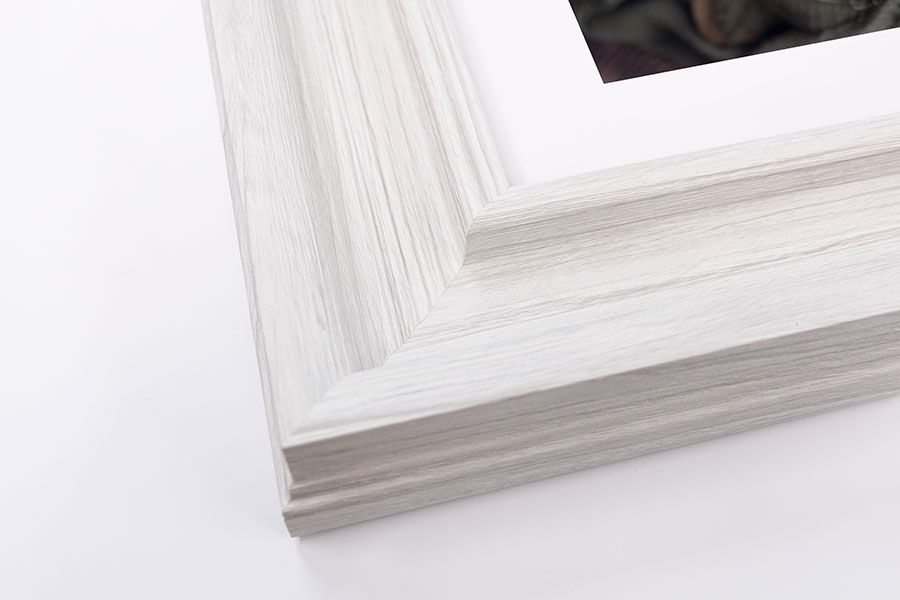 White distressed wood grain picture frame corner with white mat and photo on white background.
