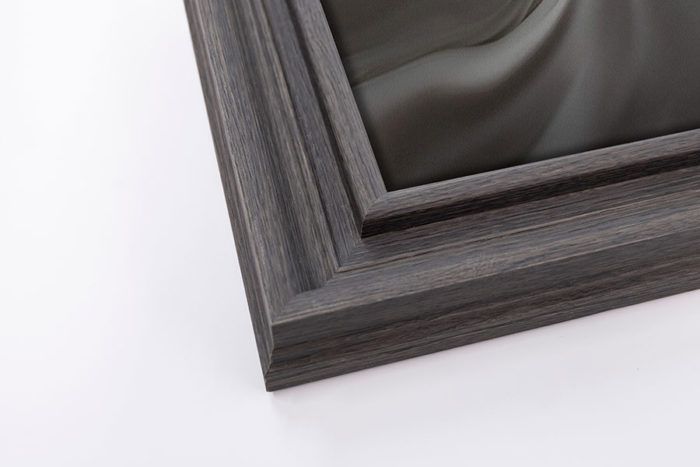 Close-up corner detail of a dark grey distressed wood picture frame on a white background.