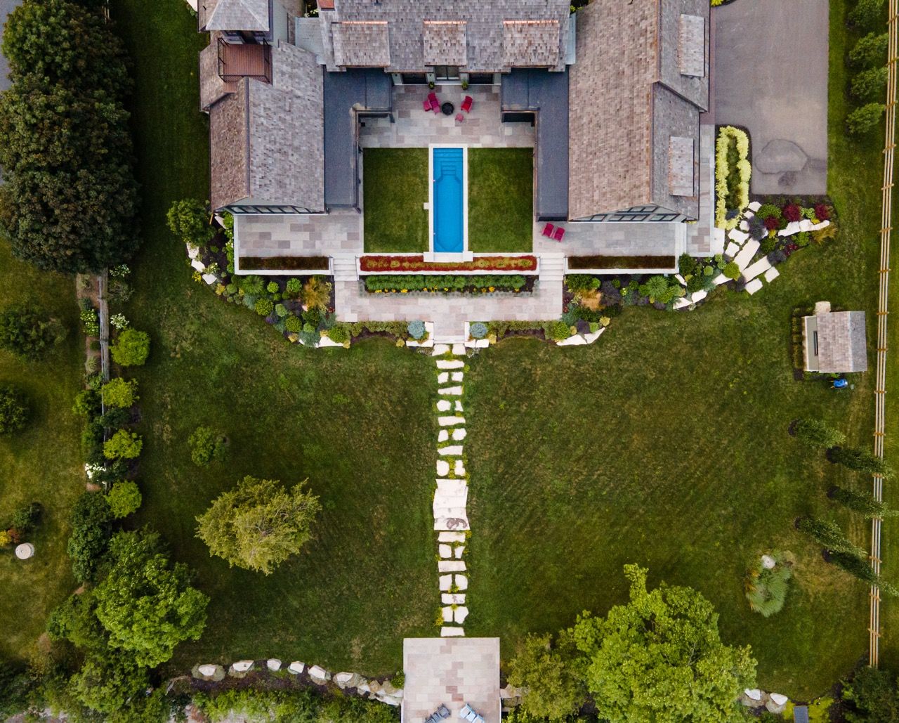 Top-down aerial view of a luxury property with a pool, symmetrical gardens, and a stone pathway leading to the estate.