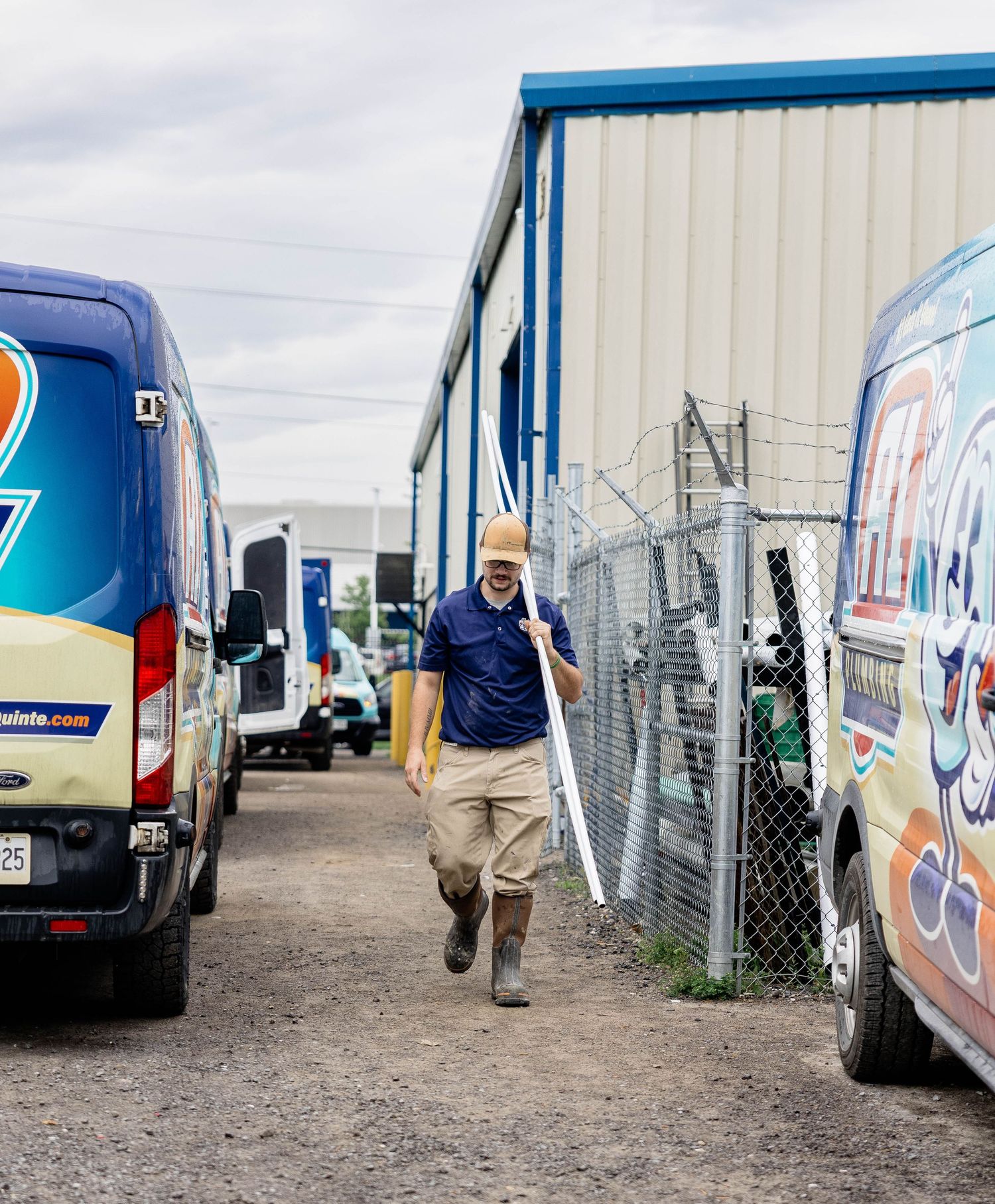 Plumber walking between branded A1 Plumbing service vans in a commercial yard.