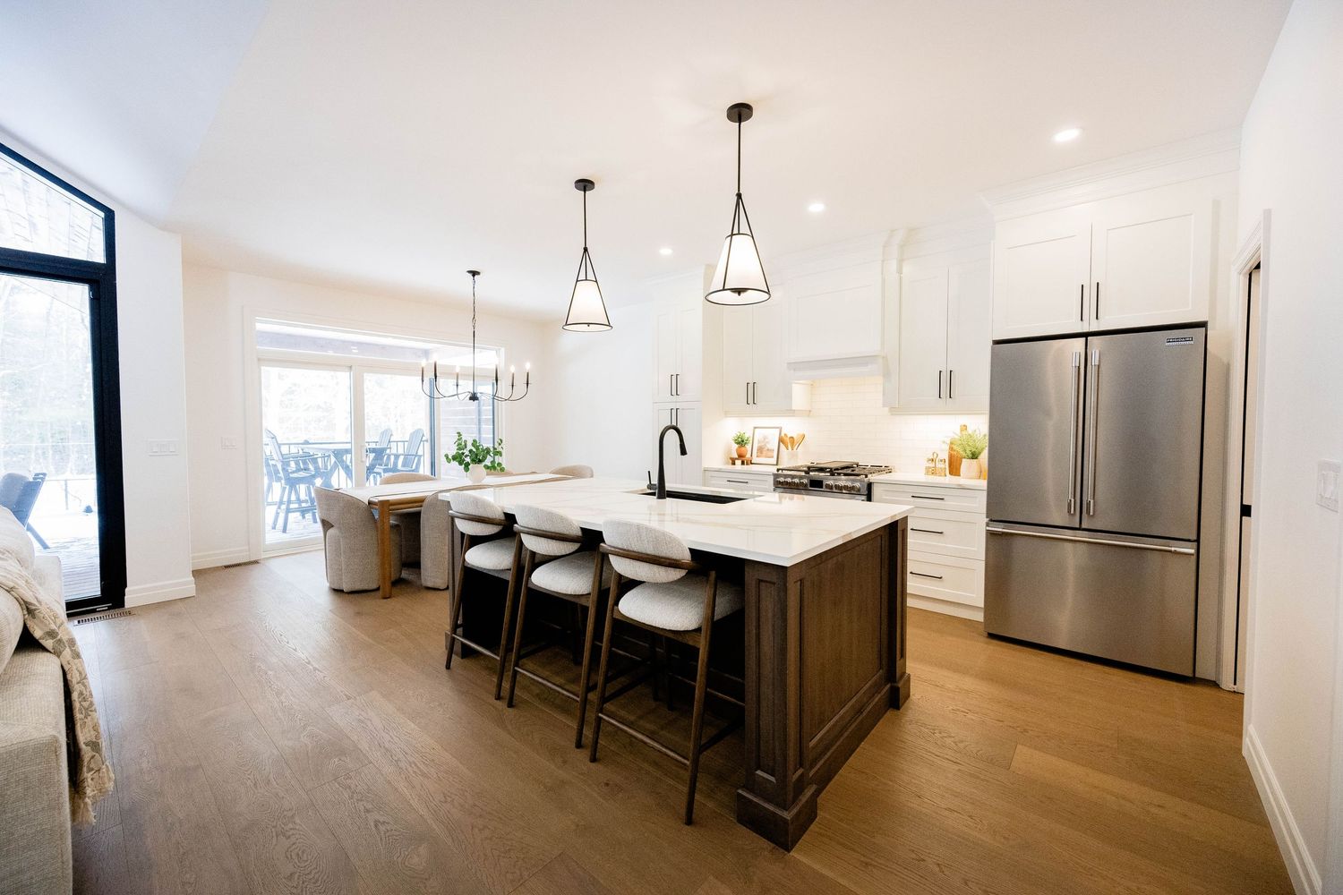 Modern open-concept kitchen featuring dark wood island, white cabinets, and stainless steel appliances.
