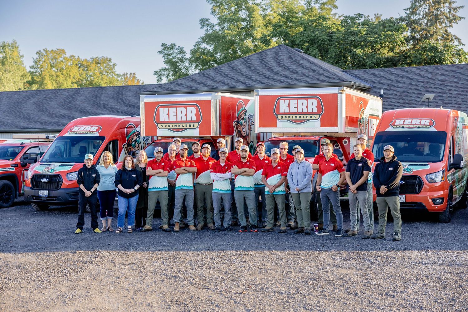 Kerr Restoration team posing in front of branded red vans at their facility in a group photo.
