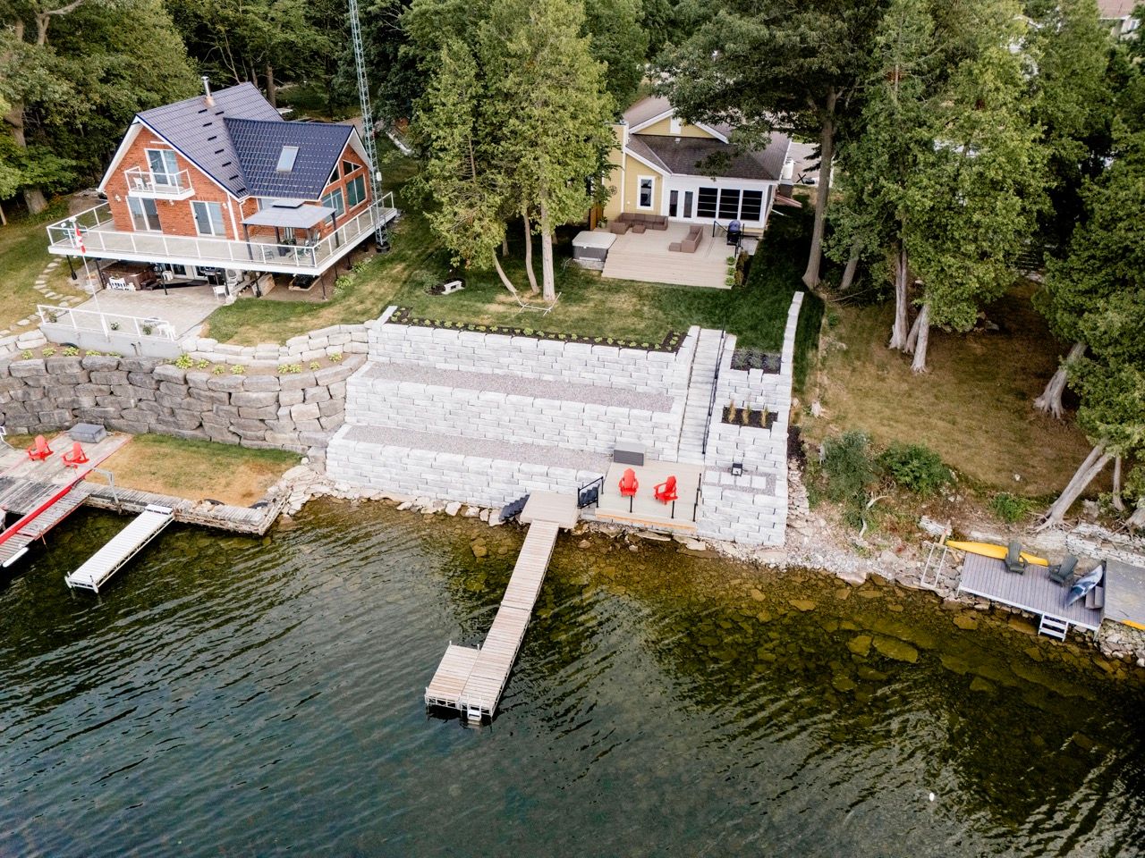 Aerial view of lakeside properties with new stone seawall, dock, and waterfront access.