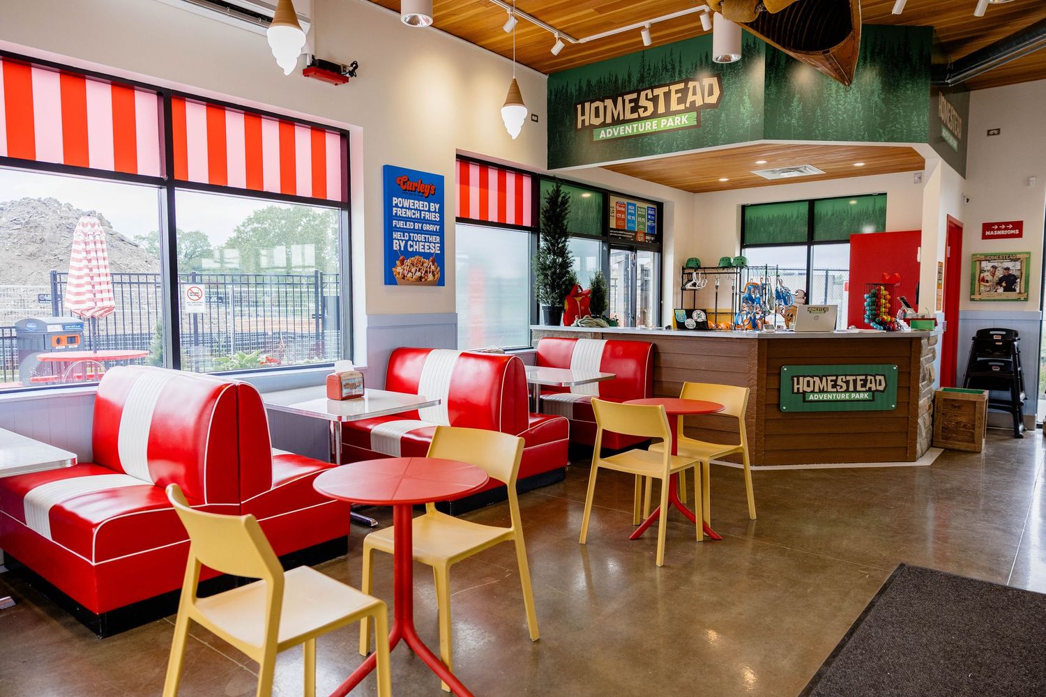Bright Homestead diner interior with red vinyl booths, striped awnings, and yellow chairs.