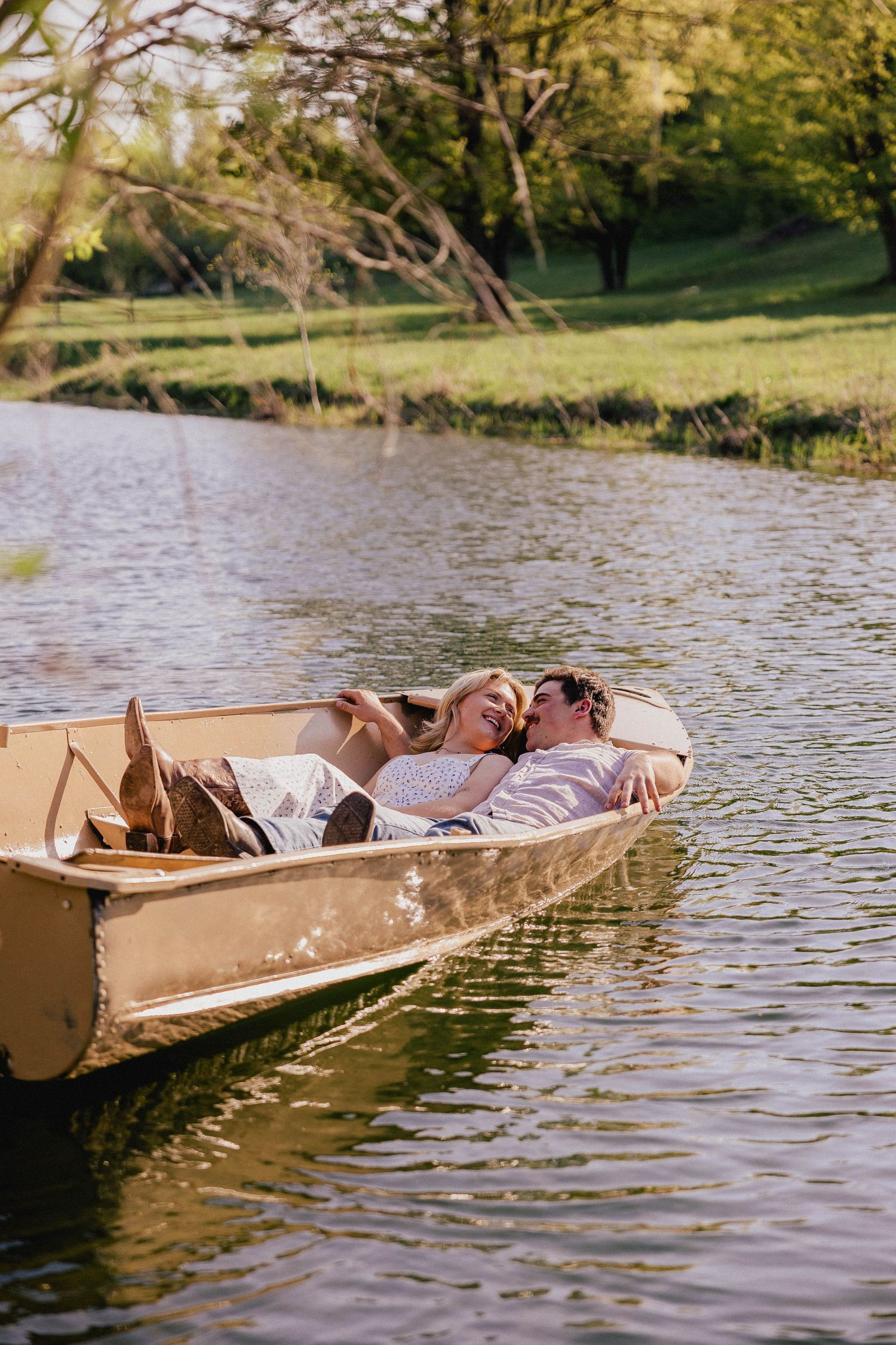Happy couple cuddling and laughing while relaxing in a rowboat on a sunlit lake.