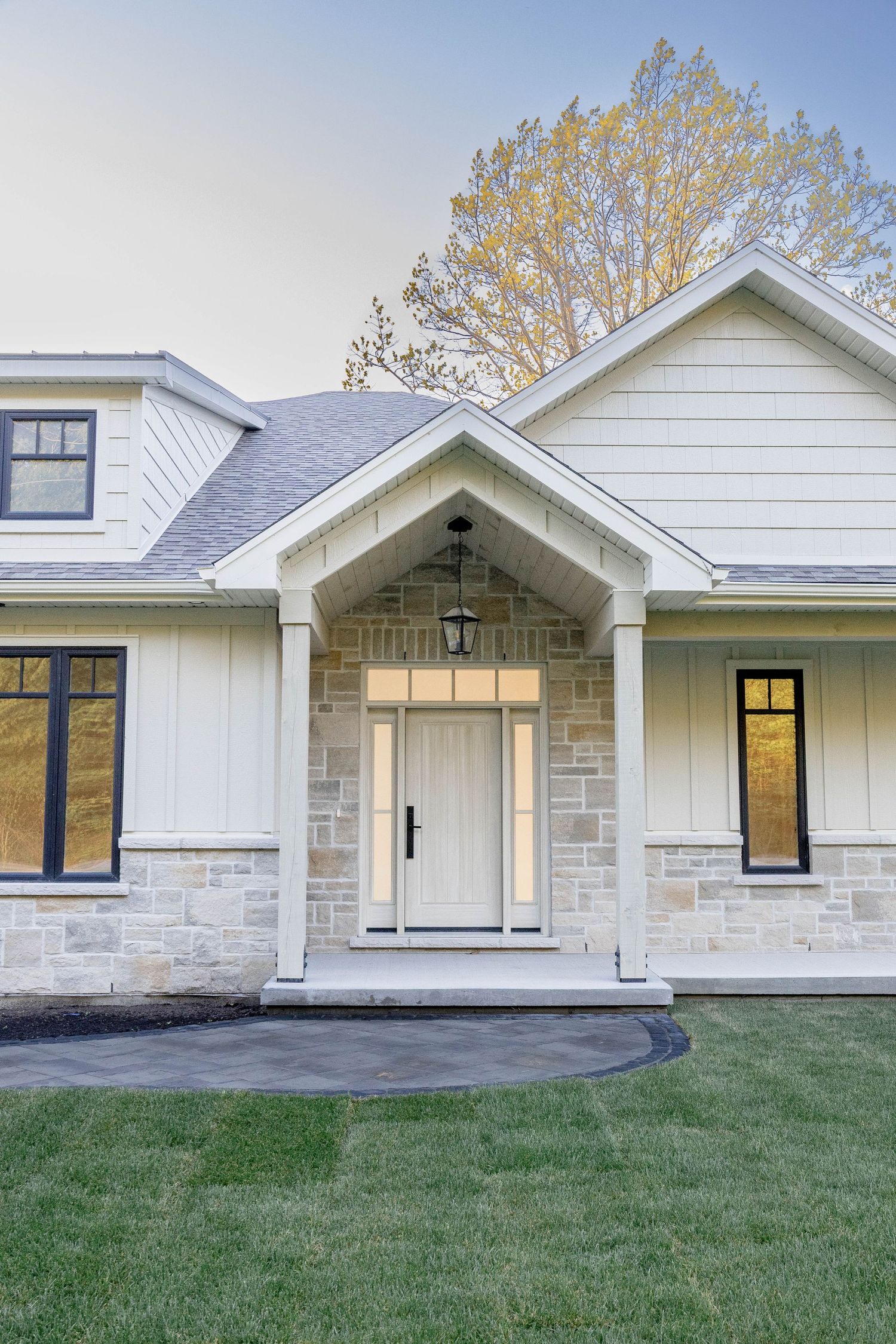 Elegant farmhouse entryway with stone accents, white columns, and lantern pendant light.