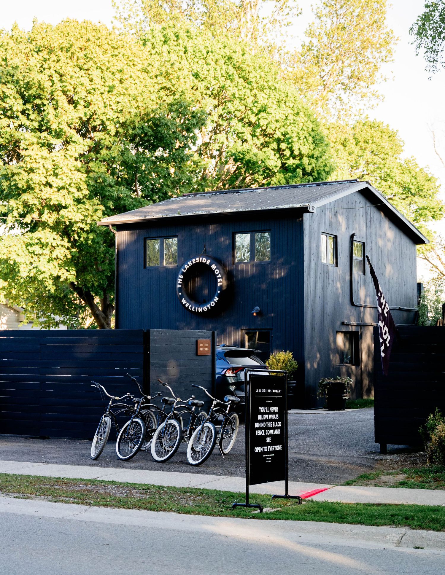 Black painted wooden building with bicycles parked outside and a wreath sign above the entrance.