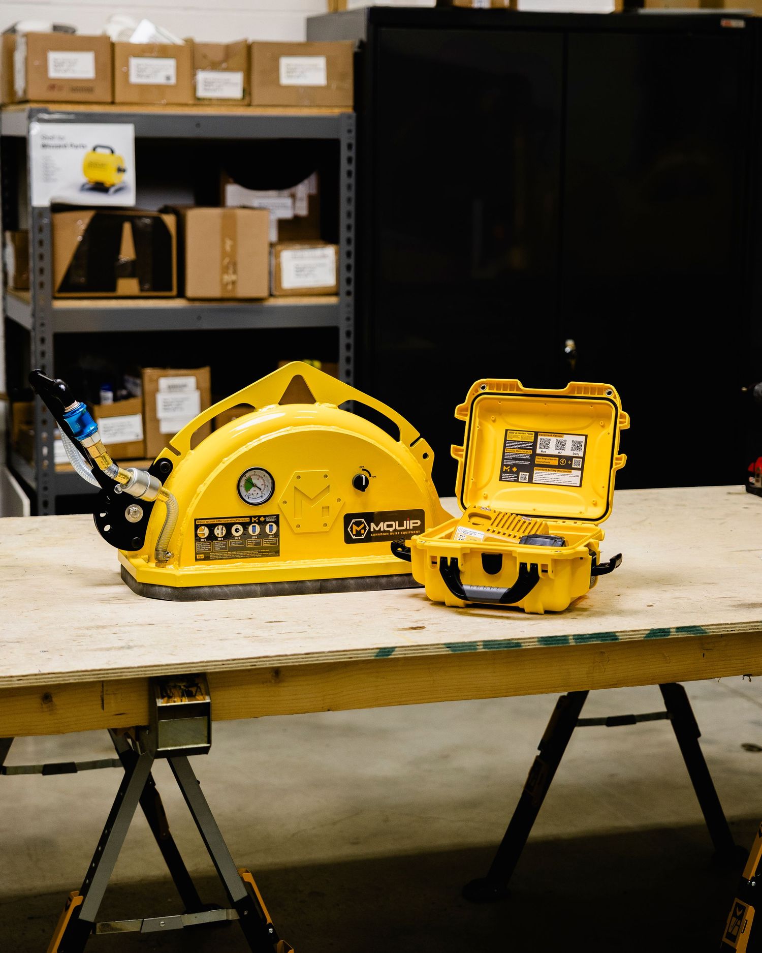 Yellow MQUIP vacuum lifting device and yellow case displayed on workbench in warehouse.
