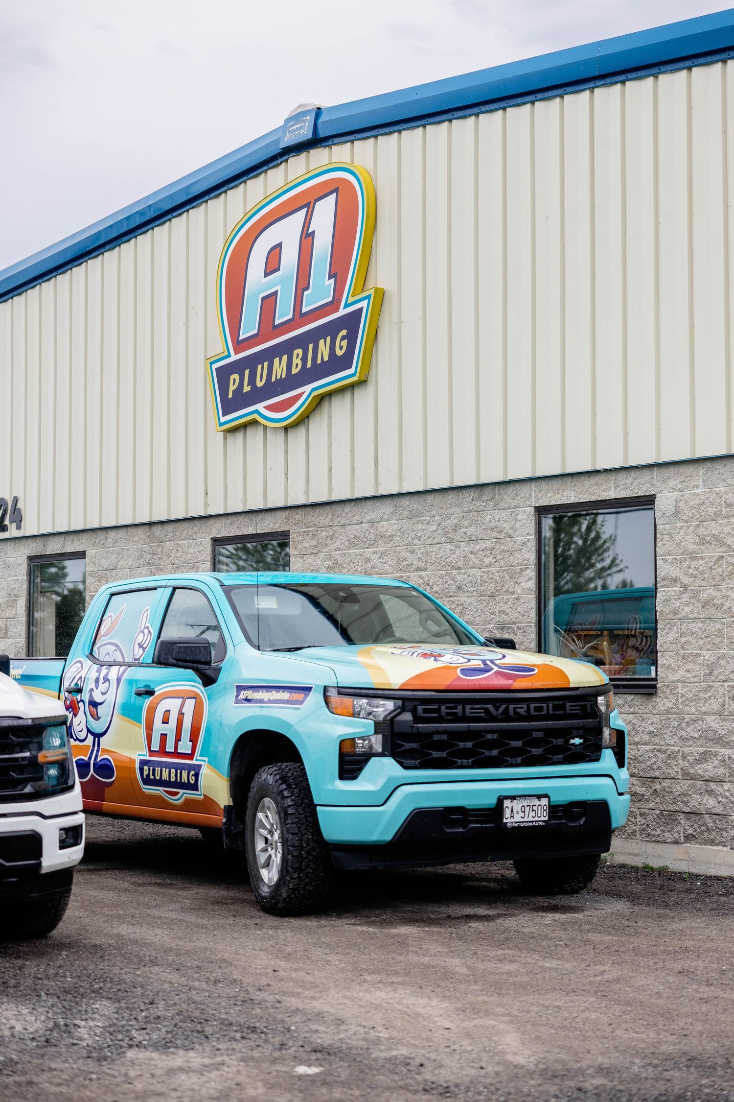 Colorful A1 Plumbing wrapped Chevrolet truck parked outside the A1 Plumbing headquarters building.