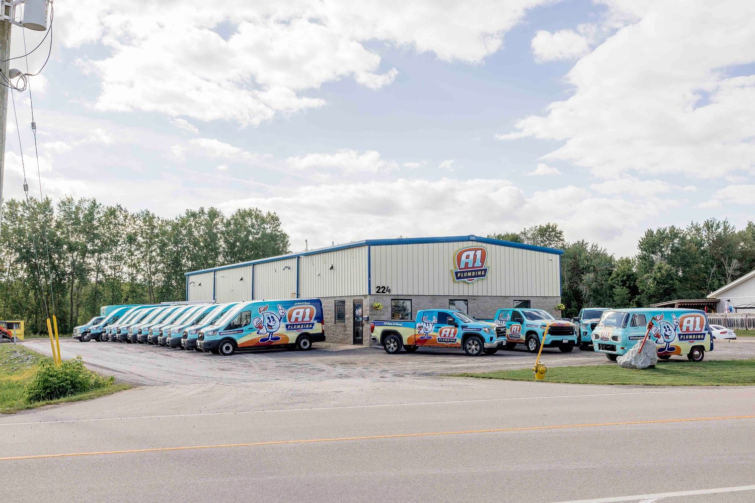 Fleet of colorful branded service vans parked outside a commercial building with blue roof and company logo signage.