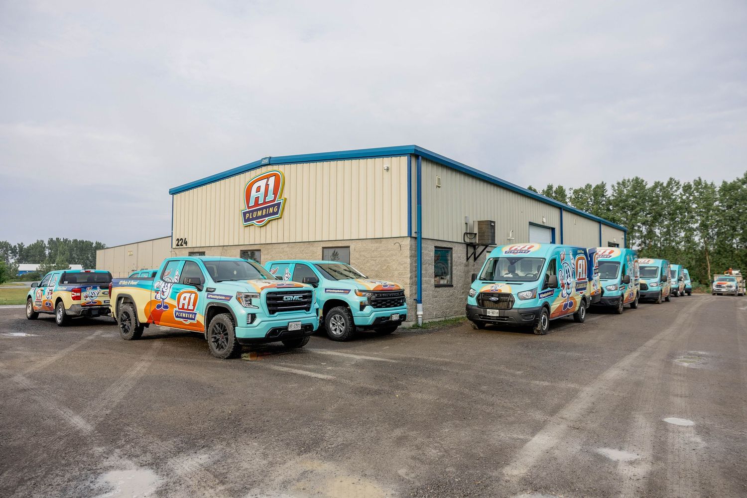 A1 service company fleet of branded trucks and vans parked outside a commercial building in a paved lot.