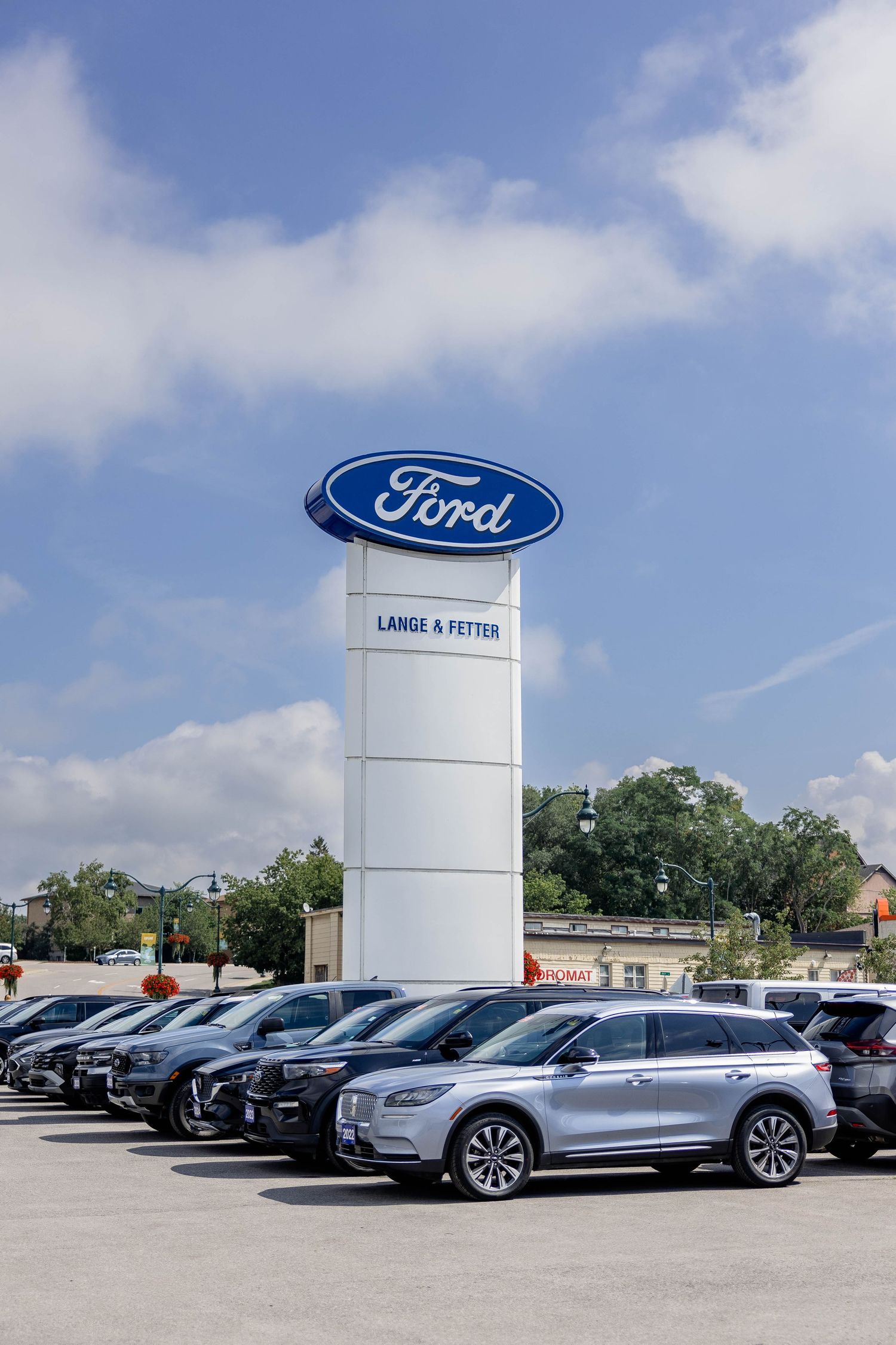 Lange-A-Fetter Ford dealership with branded pylon sign and row of new SUVs on sunny day.