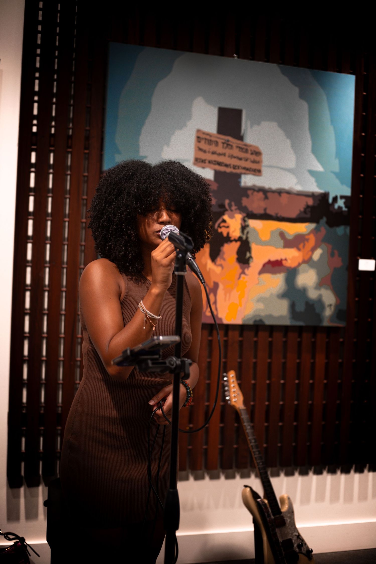 Close-up of Black female vocalist singing passionately at microphone stand in studio.