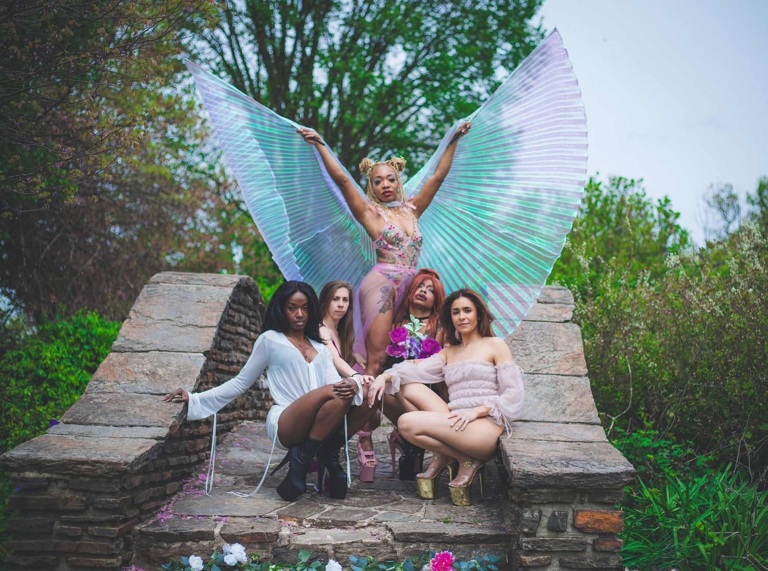 Group of five women posing outdoors with one wearing decorative butterfly wings.