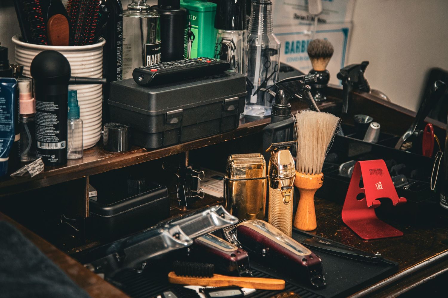 Vintage barbershop tools including straight razors, brushes, and grooming supplies on a wooden counter.