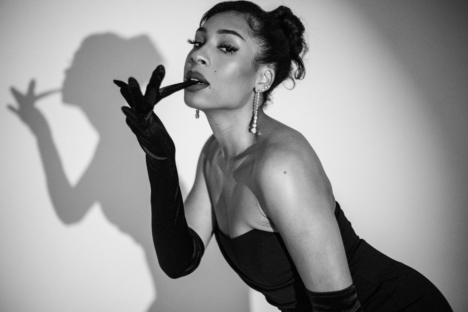Black and white portrait of elegant woman in strapless dress with long gloves striking a pose.