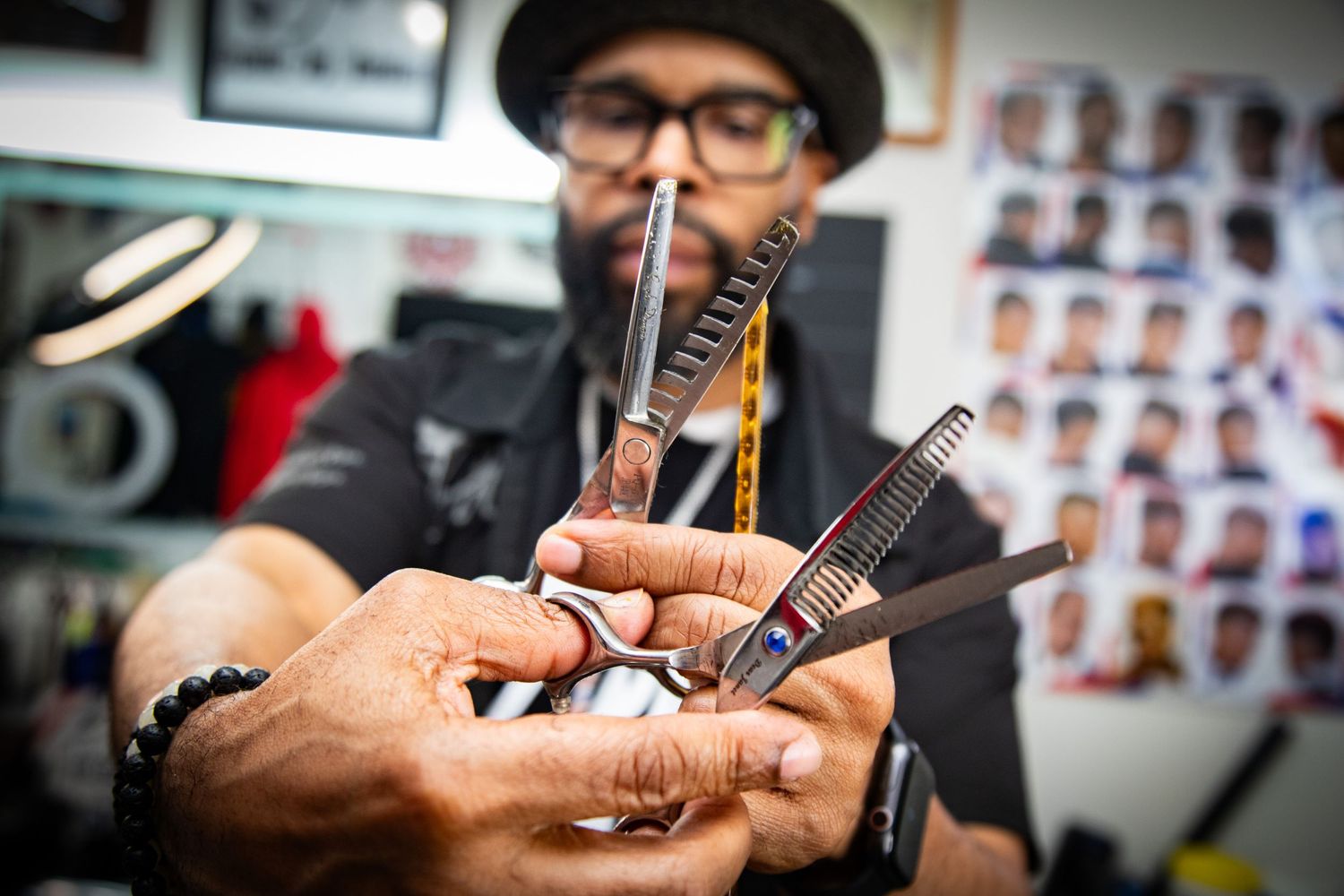 Close-up of a barber holding scissors and combs in a professional barbershop setting.