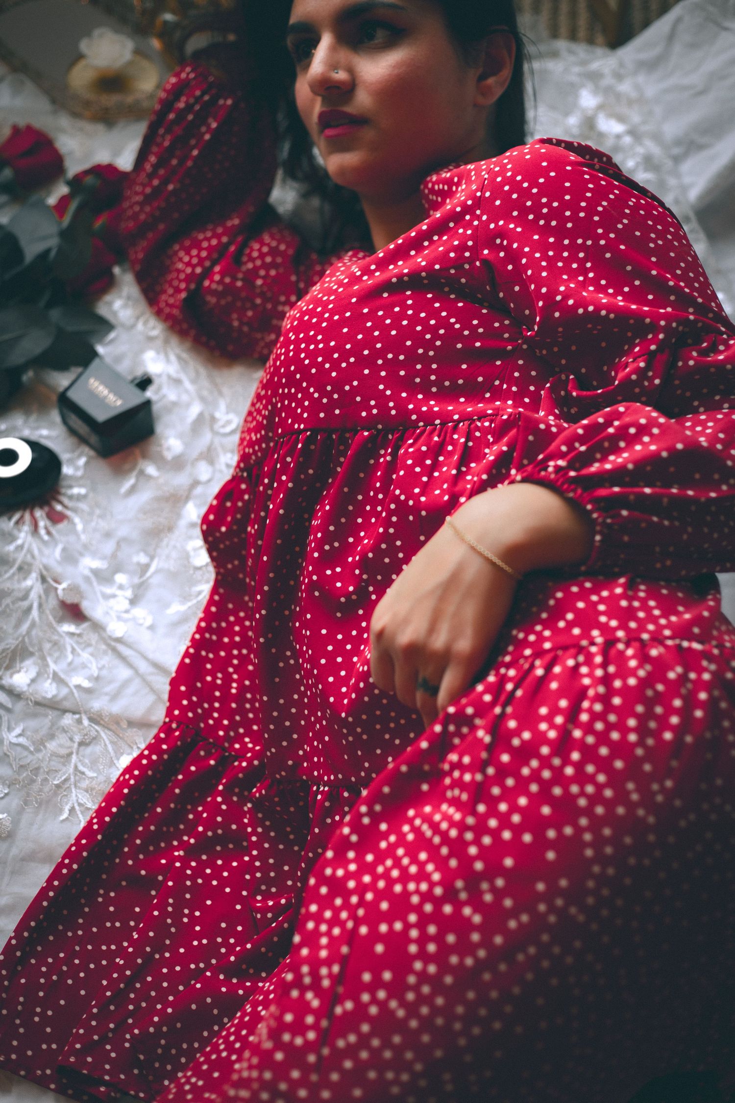 Woman in a red polka dot dress lying on the floor surrounded by accessories.